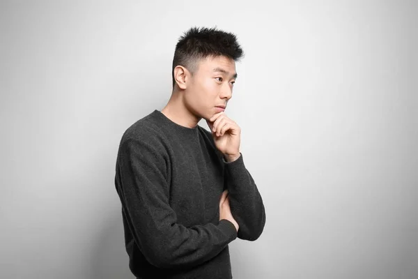 Portret van jonge Aziatische man op lichte achtergrond — Stockfoto
