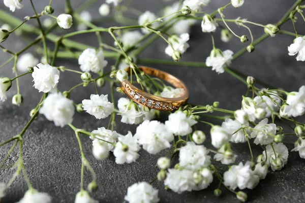 Hermoso anillo de compromiso y flor en la mesa gris, primer plano — Foto de Stock