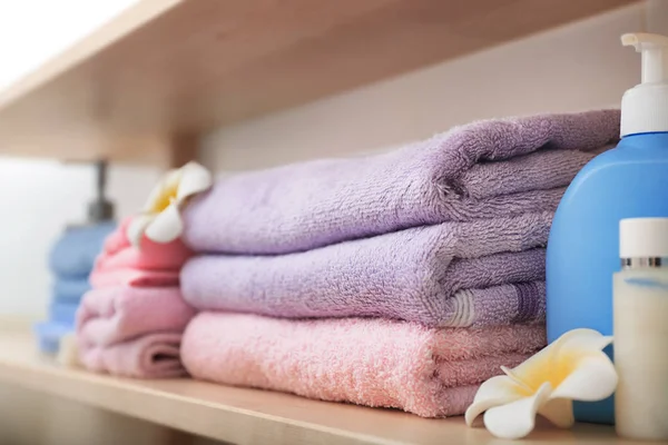 Clean towels and cosmetics on shelf in bathroom