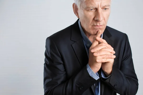 Portrait of thoughtful mature man in dark suit on light background — Stock Photo, Image