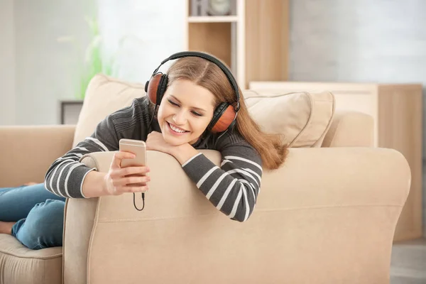 Mooie vrouw luisteren naar muziek tijdens het rusten op de sofa thuis — Stockfoto
