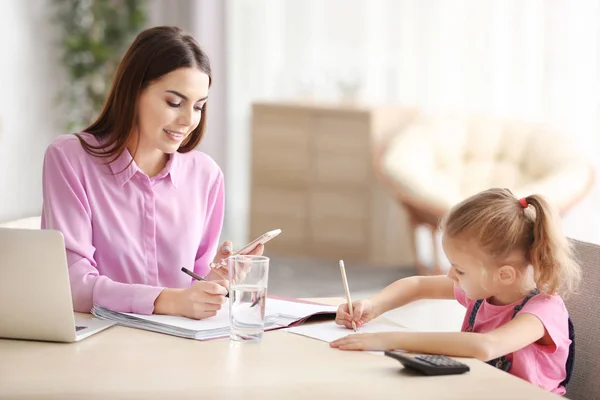 Jeune femme occupée avec sa fille au bureau à la maison — Photo