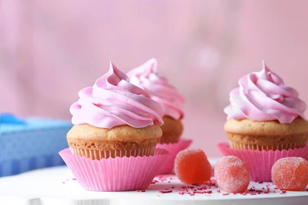 Placa com deliciosos cupcakes e doces de marmelada na mesa — Fotografia de Stock