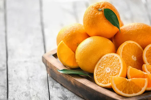 Tray with fresh cut oranges on wooden table — Stock Photo, Image