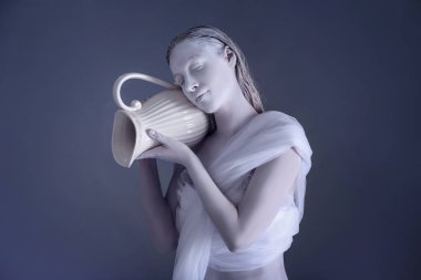 Güzel genç kadın inanılmaz vücut-sanat ile kova olarak gri bir arka plana dayanır. Zodyak işaretleri kavramı