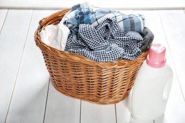 Sepet kirli elbise ve çamaşır deterjanı Beyaz ahşap zemin üzerinde ve