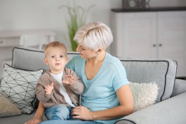 Genç anne bebeğini evde kanepede oturan ile