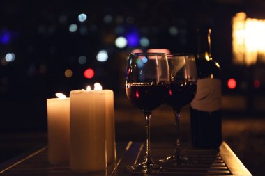 Masada açık havada geceleri yanan mumlar ve şarap ile romantik kompozisyon