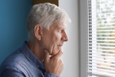 Pencere kapalı yakınındaki düşünceli olgun adam