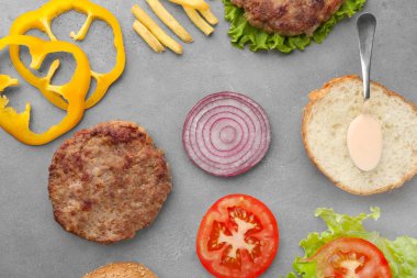 Gri zemin üzerine lezzetli burger için malzemeler ile kompozisyon
