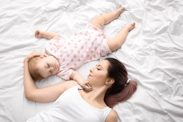 Young mother and cute sleeping baby on bed — Stock Photo, Image