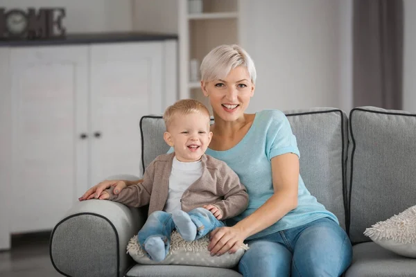 Atraente jovem mãe com seu bebê no sofá em casa — Fotografia de Stock