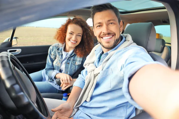 Szczęśliwa Młoda para biorąc selfie w samochodzie — Zdjęcie stockowe