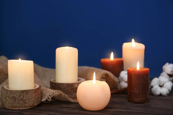 Hořící svíčky na stole na barevném pozadí — Stock fotografie