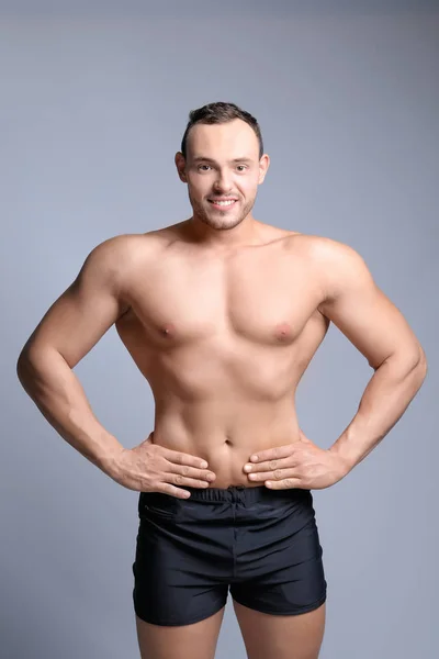 Muscular young bodybuilder on grey background — Stock Photo, Image