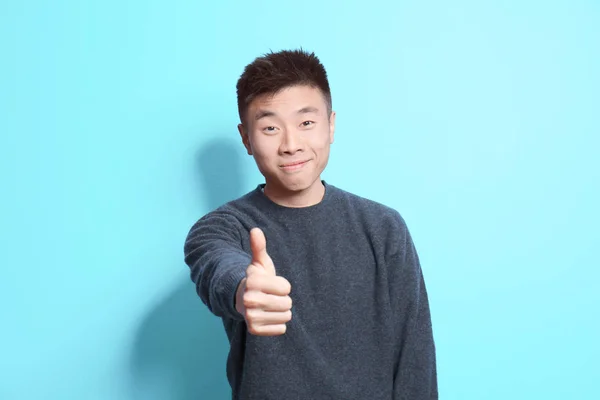 Portret van jonge Aziatische man op kleur achtergrond — Stockfoto