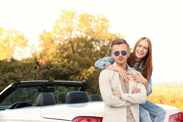 Heureux jeune couple étreignant près de la voiture — Photo