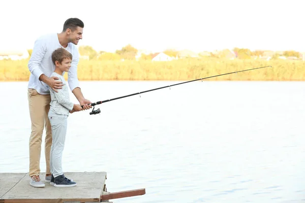 Padre y su hijo pescando desde el muelle en el río — Foto de Stock