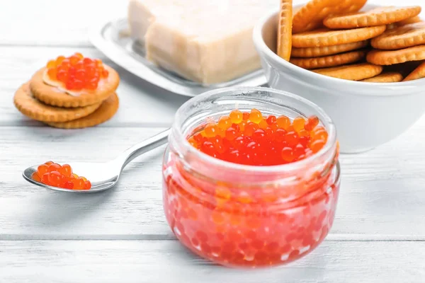 Tarro de vidrio y cuchara con caviar rojo en la mesa —  Fotos de Stock