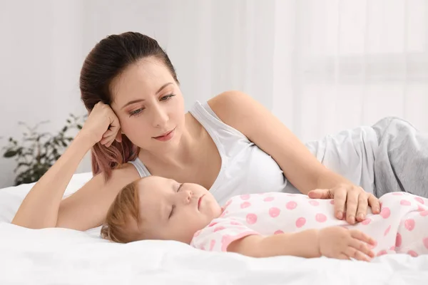 Ibu muda dan bayi tidur yang lucu di tempat tidur di rumah — Stok Foto