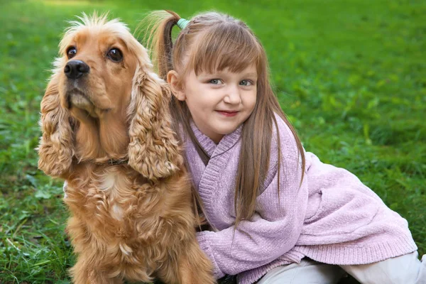 Petite fille mignonne avec chien drôle sur herbe verte — Photo