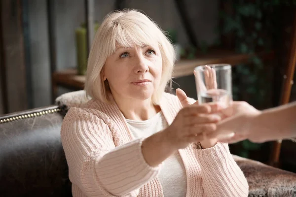 Main de jeune femme donnant du verre avec de l'eau à dame mature — Photo