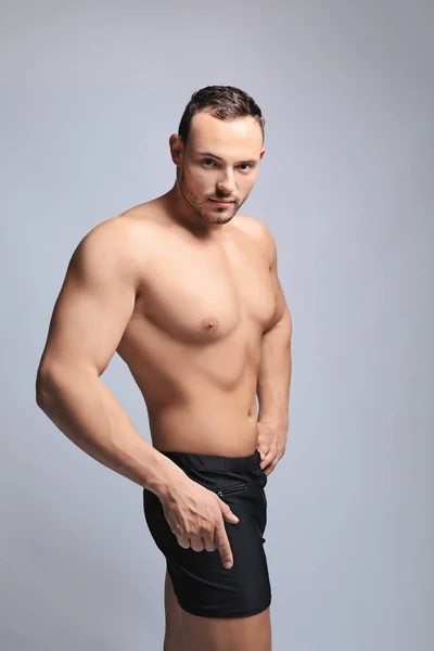 Muskulöser junger Bodybuilder auf grauem Hintergrund — Stockfoto