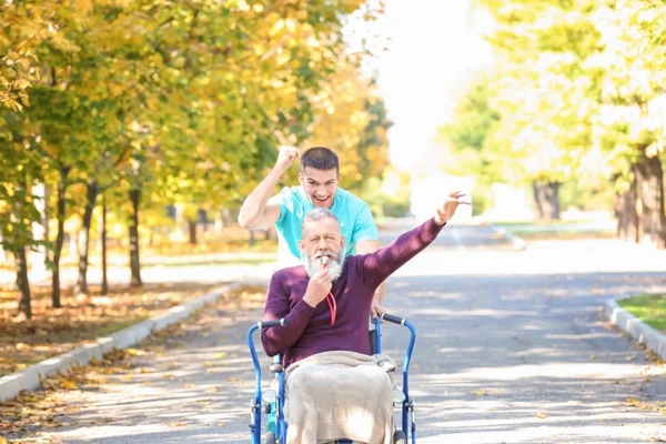 Junge Betreuerin läuft mit Senioren im Park — Stockfoto