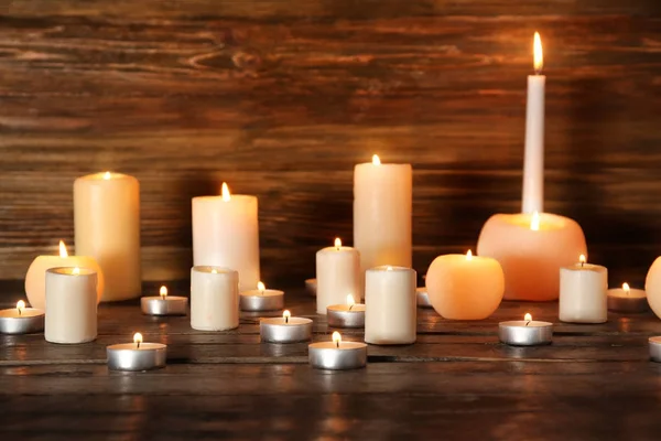 Veel brandende kaarsen op houten achtergrond — Stockfoto