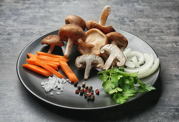 Prato com cogumelos shiitake crus e legumes na mesa — Fotografia de Stock