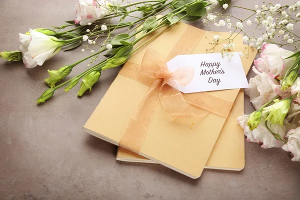 Karte mit den Worten "Happy Mother 's Day", Notizbüchern und Blumen auf grauem Hintergrund — Stockfoto