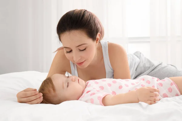 Jovem mãe e bebê adormecido bonito na cama em casa — Fotografia de Stock