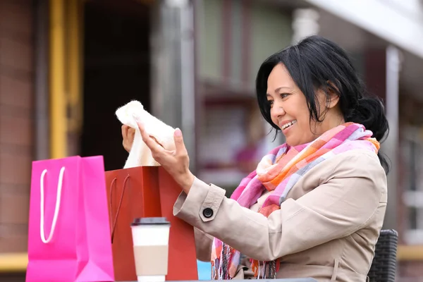 Vacker mogen kvinna att ta kläder ur shopping väska utomhus — Stockfoto