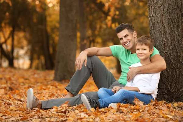 Padre e suo figlio riposano vicino all'albero nel parco — Foto Stock