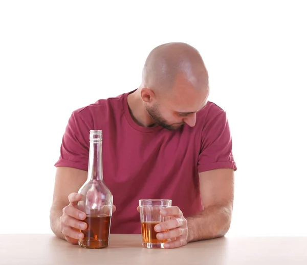 Пьяный мужчина сидит за столом с виски на белом фоне. Концепция алкоголизма — стоковое фото