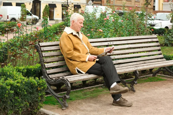 Красивий зрілий чоловік читає газету на лавці на відкритому повітрі — стокове фото