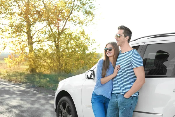 Bonito jovem casal de pé perto do carro ao ar livre — Fotografia de Stock