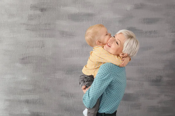 Ung mamma håller hennes baby på grå bakgrund — Stockfoto