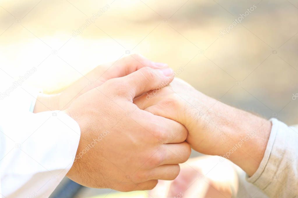 Young caregiver holding hands with senior man, closeup