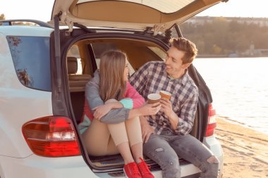 Kahve araba gövde Nehri yakınında oturan ile güzel genç Çift