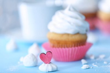 Beze öpücükle dekoratif kalp ve arka plan üzerinde bulanık cupcake