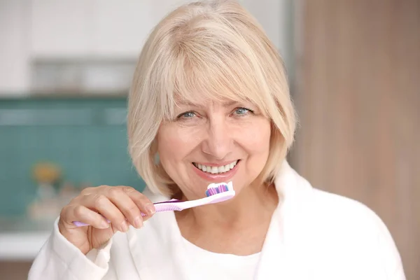 Mujer madura limpiando dientes en casa — Foto de Stock