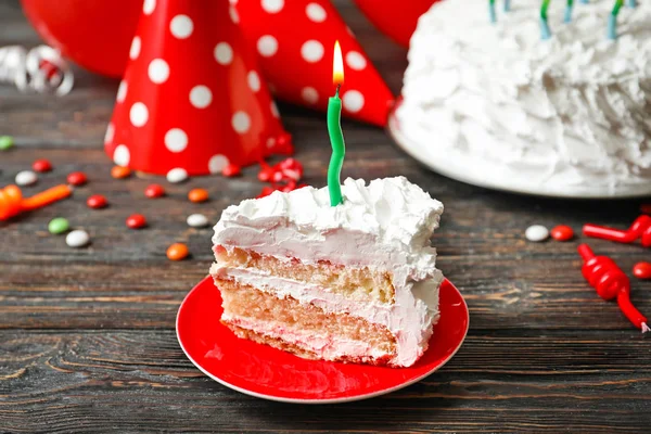 Piece of birthday cake with candle on table — Stock Photo, Image