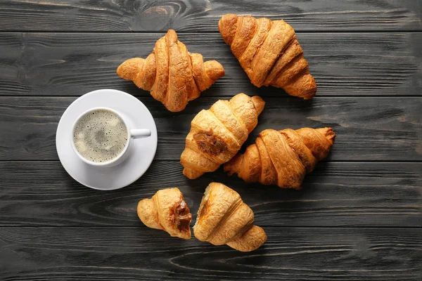Lekkere croissants en kopje koffie op houten achtergrond — Stockfoto