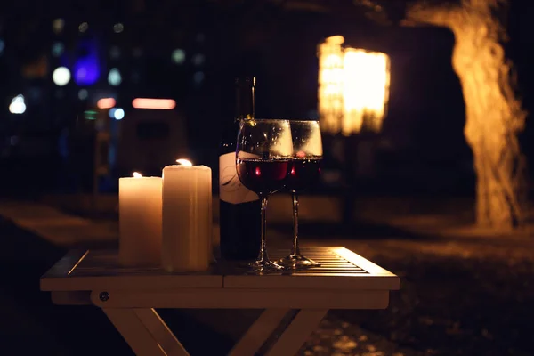 Романтическая композиция с горящими свечами и вином на открытом воздухе ночью — стоковое фото