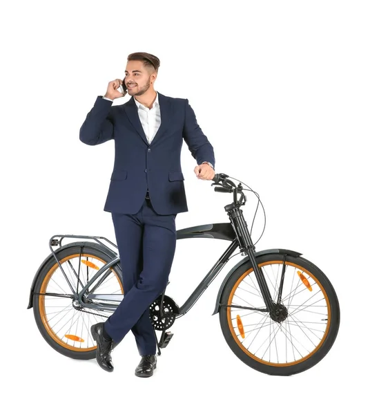Joven hombre de negocios guapo con bicicleta hablando por teléfono sobre fondo blanco — Foto de Stock