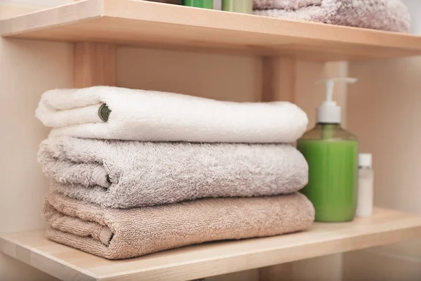 Clean towels and cosmetics on shelf in bathroom