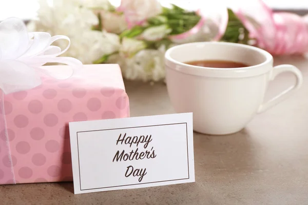 Cartão com palavras "Feliz Dia das Mães", caixa de presente e xícara de chá na mesa — Fotografia de Stock