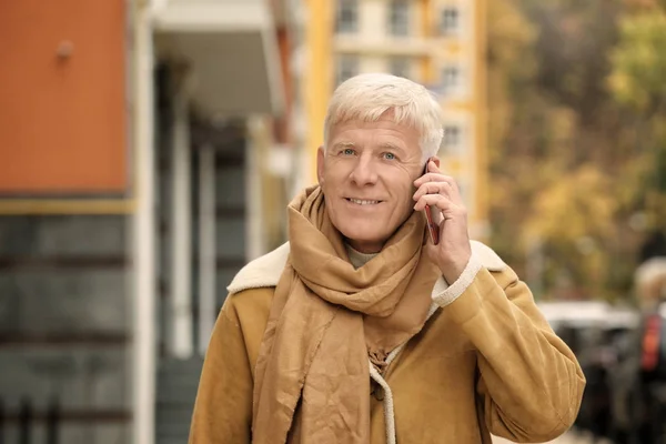 Knappe volwassen man praten over telefoon buitenshuis — Stockfoto