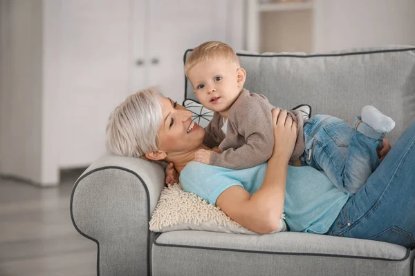 Приваблива молода мати зі своєю дитиною на дивані вдома — стокове фото